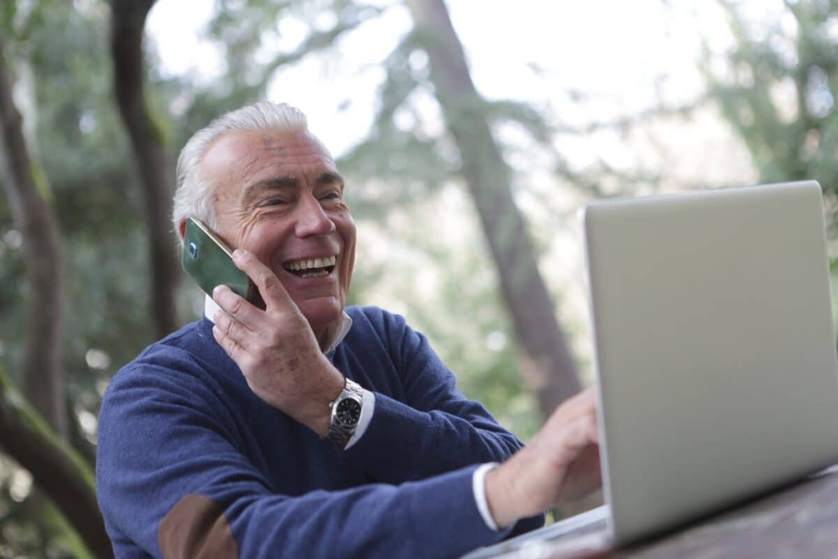 Un senior au téléphone et sur son ordinateur